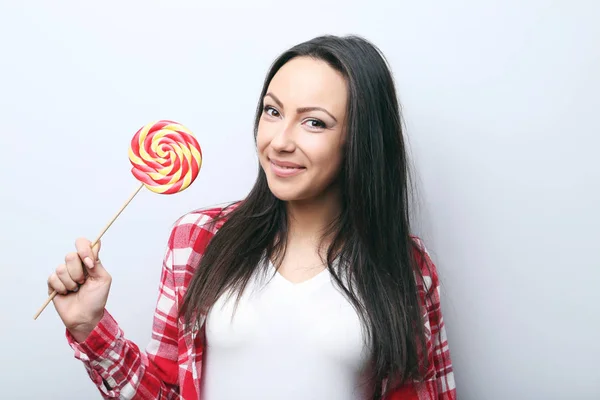 Ung kvinna med lollipop på grå bakgrund — Stockfoto