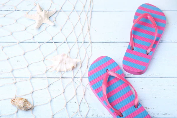 Flip flops with fishnet and seashells on tabletop — Stock Photo, Image