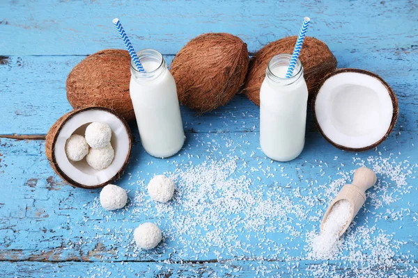 Cocos con caramelos y botellas de leche sobre la mesa — Foto de Stock