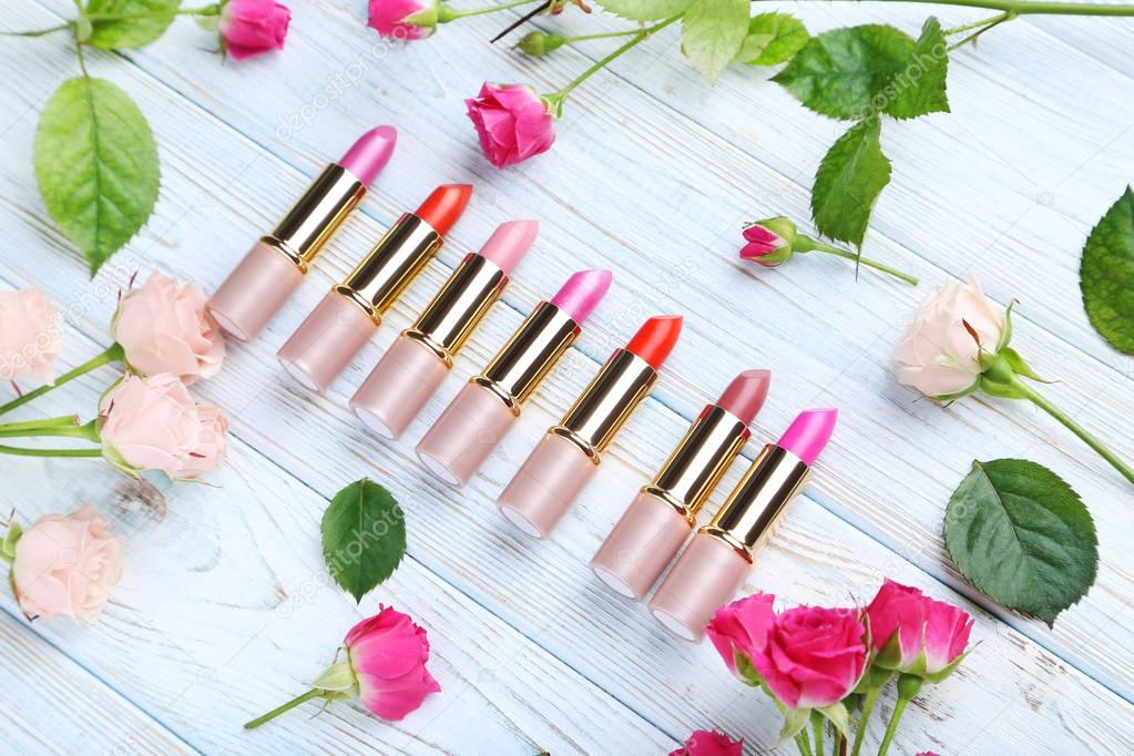 colorful lipsticks with roses on wooden tabletop