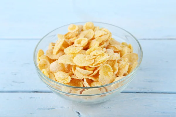 Cornflakes in bowl on blue wooden table — Stock Photo, Image