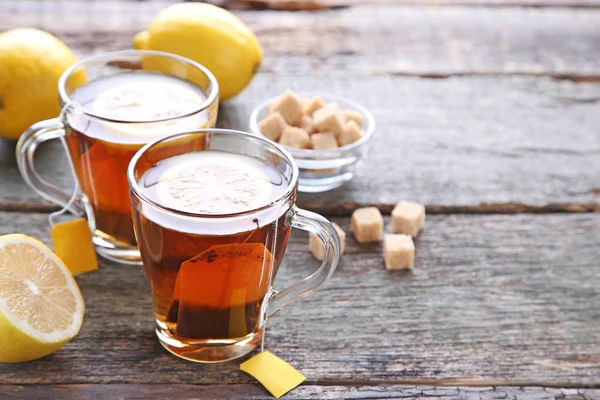 Tazze di tè con bustine di tè e limoni — Foto Stock