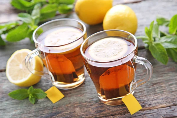 Tazze di tè con bustine di tè e limoni — Foto Stock