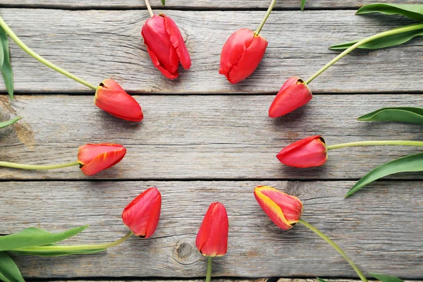 Red tulips on wooden tabletop — Stock Photo, Image