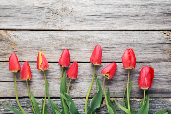 Red tulips on wooden tabletop — Stock Photo, Image