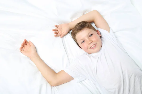 Jeune garçon dormant dans un lit blanc — Photo