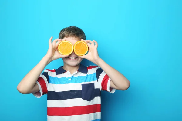 Jongen met oranje vruchten op blauwe achtergrond — Stockfoto