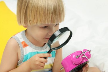 Çalar saat ve Büyüteç camı whit içinde oturan küçük çocuk