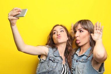 İki genç kadın selfie üzerinde sarı arka plan yapma
