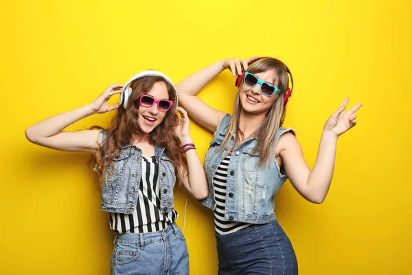 Retrato de duas jovens com óculos de sol e fones de ouvido em você — Fotografia de Stock
