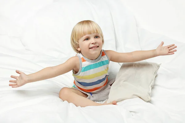 Chlapeček sedí v bílé posteli — Stock fotografie