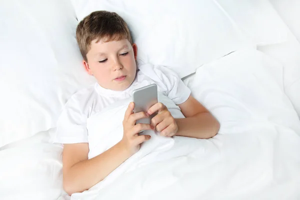 Ragazzo con smartphone a letto — Foto Stock