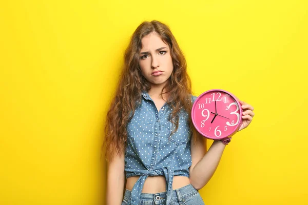 背景が黄色の丸い時計を持つ若い女性の肖像画 — ストック写真