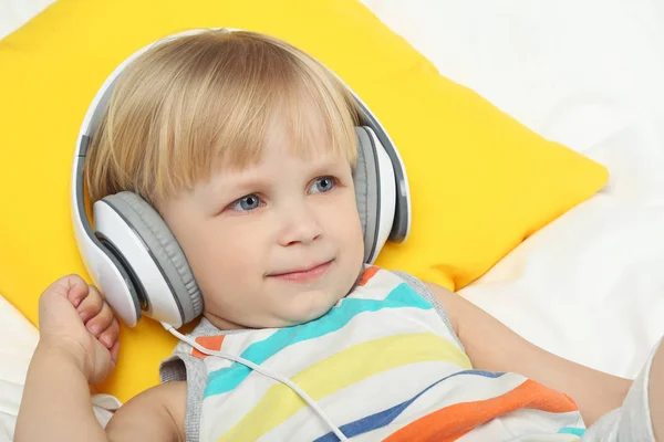Маленький хлопчик з навушниками в ліжку — стокове фото