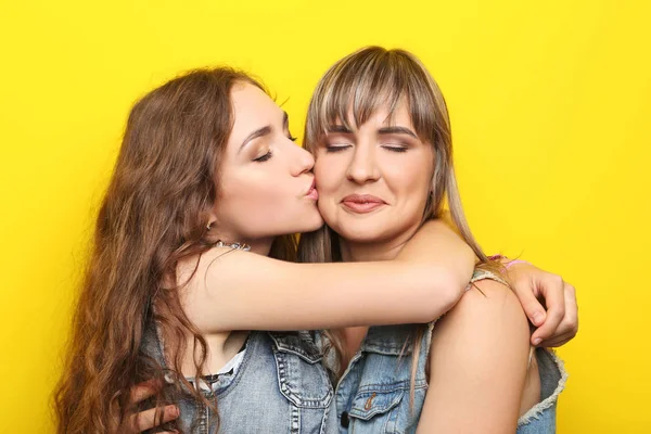 दो युवा महिला पीले पृष्ठभूमि पर एक दूसरे को गले लगा रही है — स्टॉक फ़ोटो, इमेज