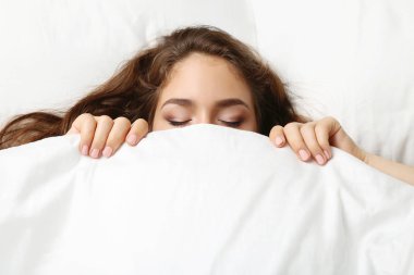 Beyaz yatakta uyuyan genç kadın