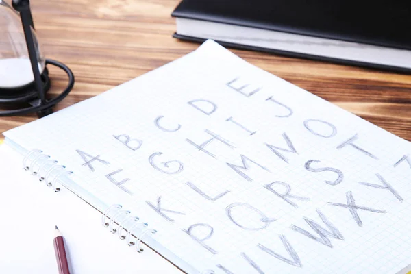 Handwritten alphabet in notebook with pencils — Stock Photo, Image