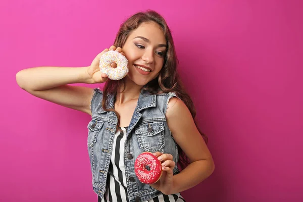 Porträt einer jungen Frau mit süßen Donuts auf rosa Hintergrund — Stockfoto