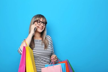 Alışveriş torbaları üzerinde mavi arka plan ile genç kadın portresi