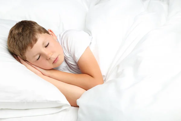 Jeune garçon dormant dans un lit blanc — Photo