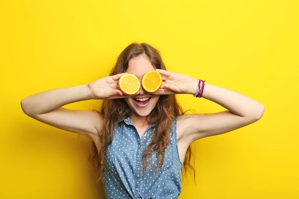 Porträtt av ung kvinna med orange frukt på gul bakgrund — Stockfoto