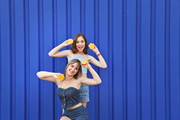 Due giovane donna con frutta arancione su sfondo blu — Foto Stock