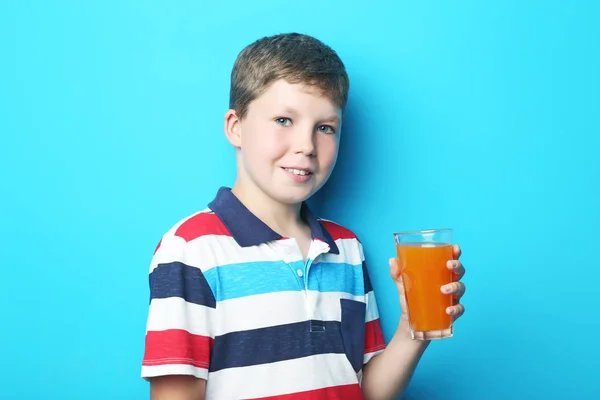 Мальчик со стаканом сока на синем фоне — стоковое фото