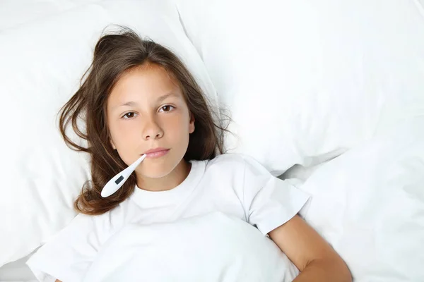 Fille malade avec thermomètre dans un lit blanc — Photo
