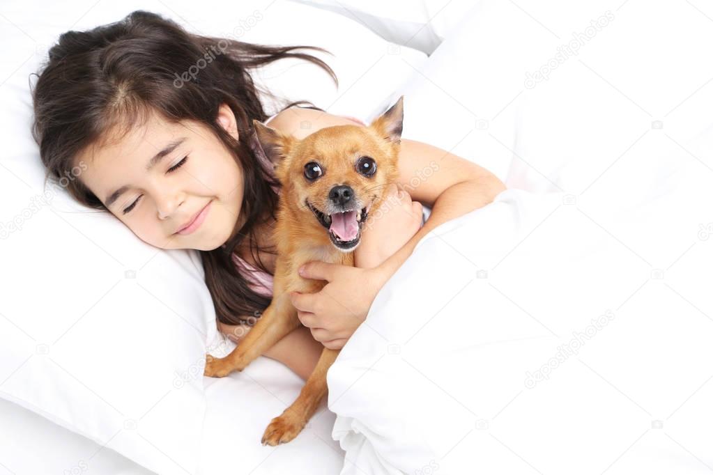 Beautiful little girl with dog sleeping in white bed