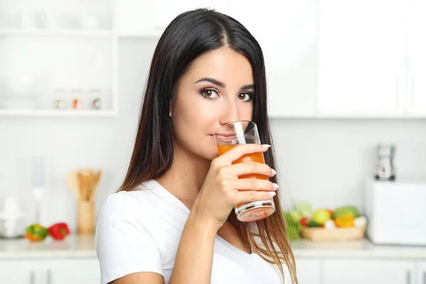 Mulher bonita bebendo suco na cozinha — Fotografia de Stock