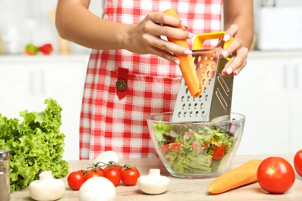 Giovane donna che cucina insalata in cucina — Foto Stock