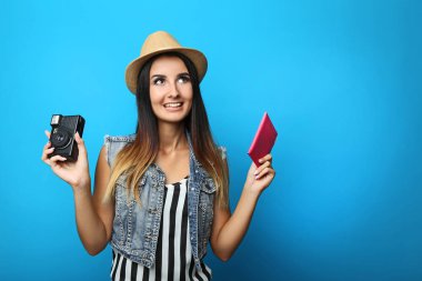 Mutlu genç kadın turist pasaportu ve retro kamera tutan