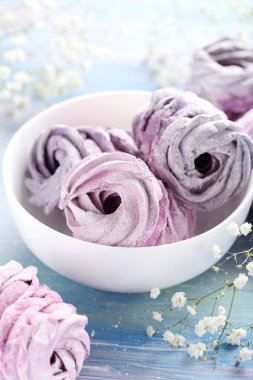 Mavi ahşap masa üzerinde bir kapta tatlı zephyr