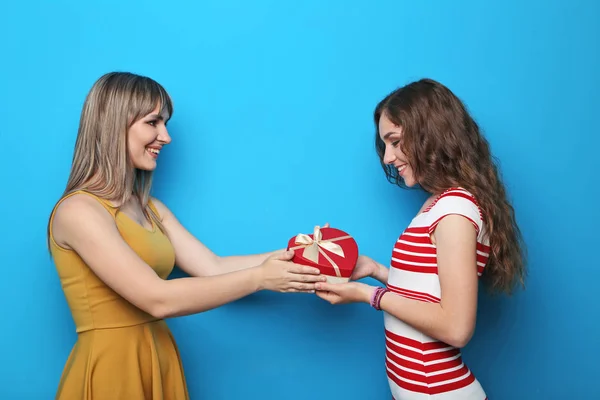 Dos mujeres jóvenes con caja de regalo sobre fondo azul — Foto de Stock