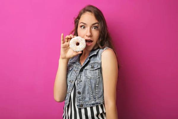 Портрет молодой женщины со сладким пончиком на розовом фоне — стоковое фото