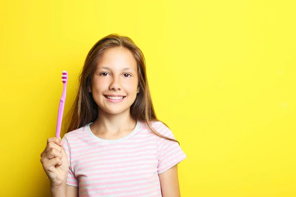 Porträt eines schönen Mädchens mit Zahnbürste auf gelbem Hintergrund — Stockfoto