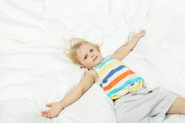 Malý chlapec ležící v bílé posteli — Stock fotografie