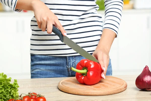 Giovane donna che taglia il pepe rosso in cucina — Foto Stock