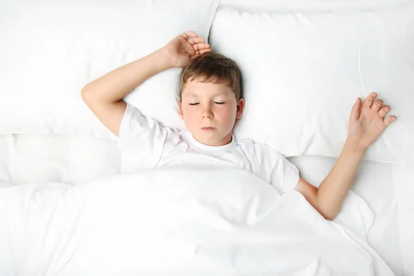 Jeune garçon dormant dans un lit blanc — Photo