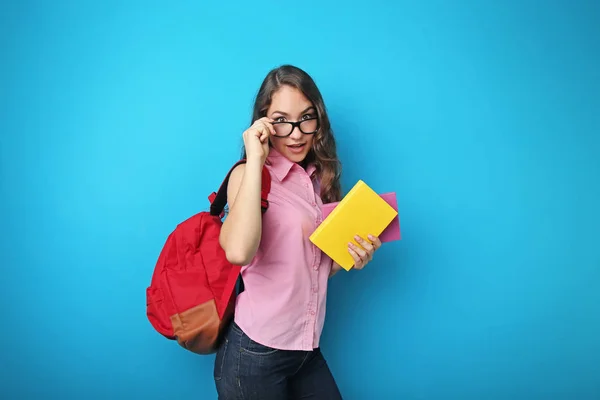 Πορτρέτο του κορίτσι φοιτητής με σακίδιο και βιβλία σχετικά με μπλε backgro — Φωτογραφία Αρχείου