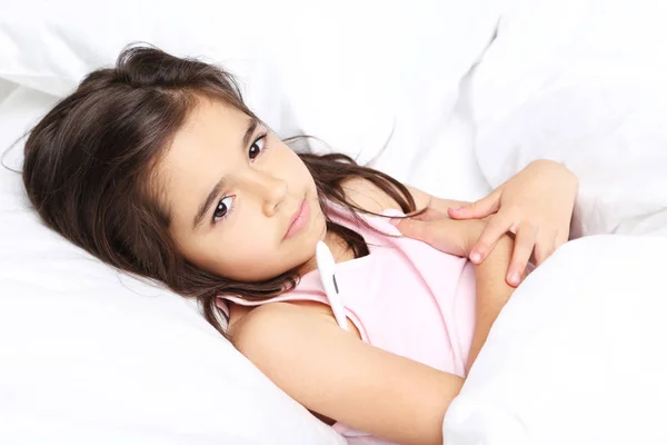 Petite fille malade avec thermomètre dans un lit blanc — Photo