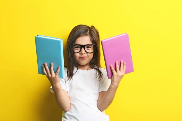 Mooi meisje met bril en boeken over gele pagina — Stockfoto