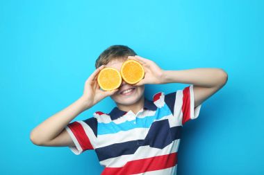 Mavi arka plan üzerinde turuncu meyve ile genç çocuk