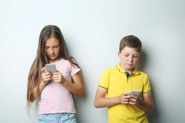 Młody chłopak i dziewczyna z smartfonów na szarym tle — Zdjęcie stockowe