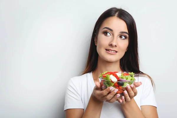 Jovem com salada de legumes em tigela de vidro no fundo cinzento — Fotografia de Stock