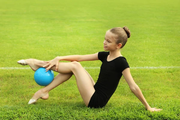 Νεαρό κορίτσι γυμναστής με μπάλα για την πράσινη χλόη — Φωτογραφία Αρχείου