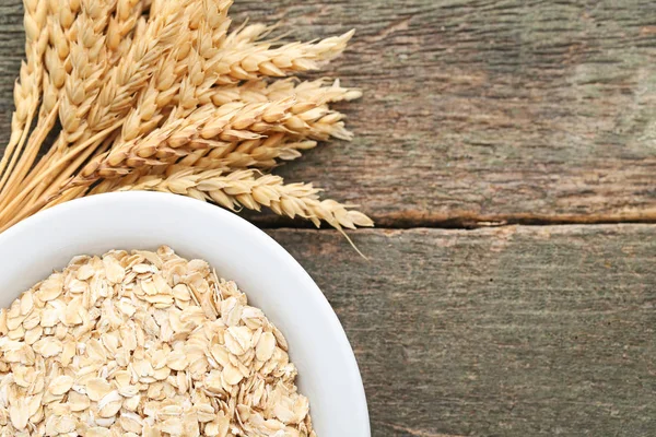 Вівсяні пластівці в мисці з пшеничними вухами — стокове фото