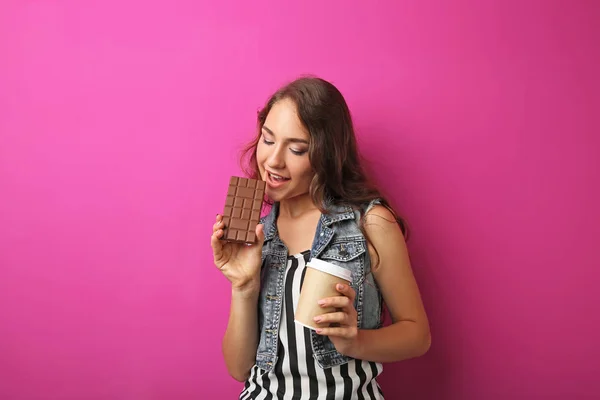 Porträt einer jungen Frau mit Schokoriegel und Getränkebecher auf dem Kopf — Stockfoto