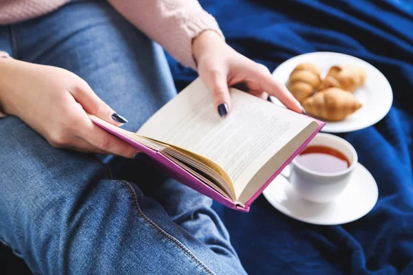 Woman with cup of tea and book sitting on blue plaid — Stock Photo, Image