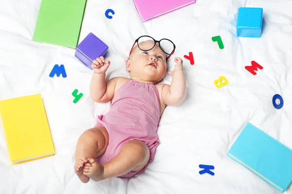 Bayi kecil yang baru lahir dengan buku dan surat di tempat tidur putih — Stok Foto